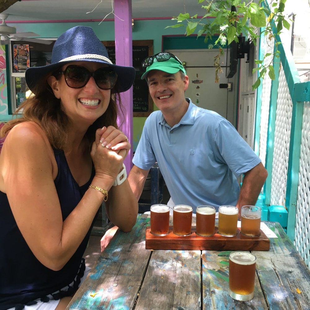 a man and a woman enjoying a flight of local craft beer