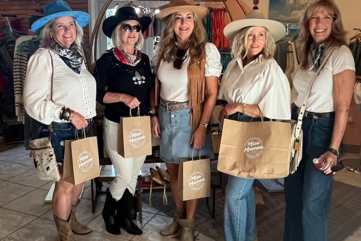 Five women holding shopping bags inside a boutique.