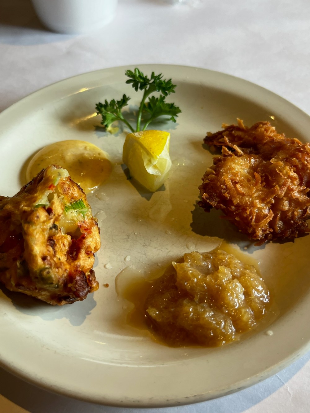 Plate with famous shrimp fritters, cocnut shrimp sauce, lemon wedge, and herbs garnish at shrimp shack in islamorada